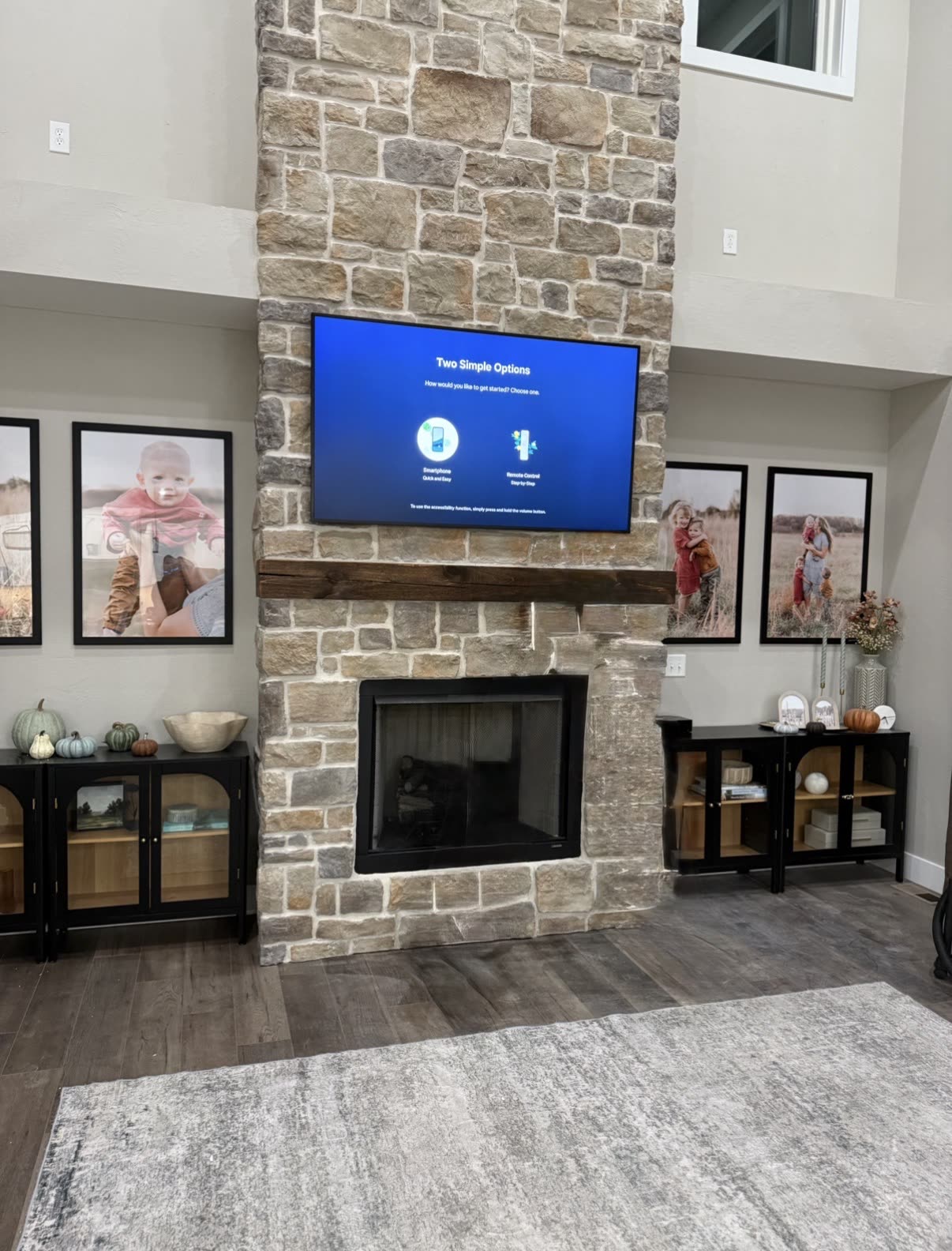 TV mounted on a floor-to-ceiling stone fireplace above a timber mantel