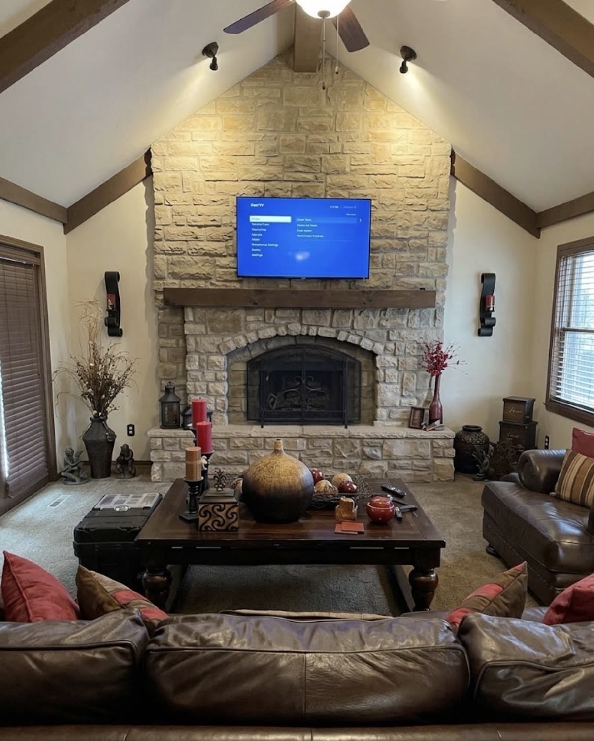 TV mounted above an arched stone fireplace in a vaulted living room