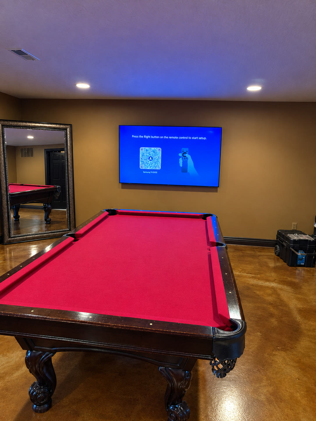 TV mounted in a game room above a red felt pool table